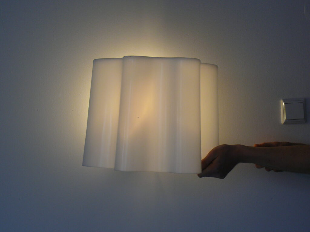 Szczecin - Lampa wykonana z tworzywa sztucznego, ukazująca proces obróbki tworzyw sztucznych. W tle widoczna ściana, co podkreśla jej nowoczesny design. Idealna jako przykład wyrobu producenta elementów z tworzyw sztucznych.